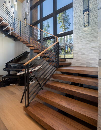 Elegant interior staircase featuring wooden steps, modern railings, and large windows that allow natural light to illuminate the space.
