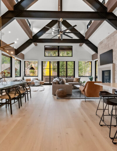 A modern, spacious interior with high ceilings, large windows, and a blend of dining and living areas featuring natural wood and stone elements.