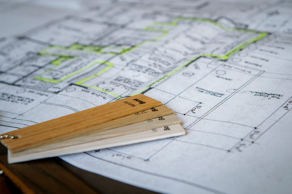 Planning a hardwood flooring replacement project with wood samples and floor layout drawings.