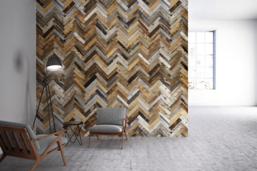 A modern interior with a herringbone patterned wood wall, a cozy chair, a lamp, and a bright window letting in natural light.