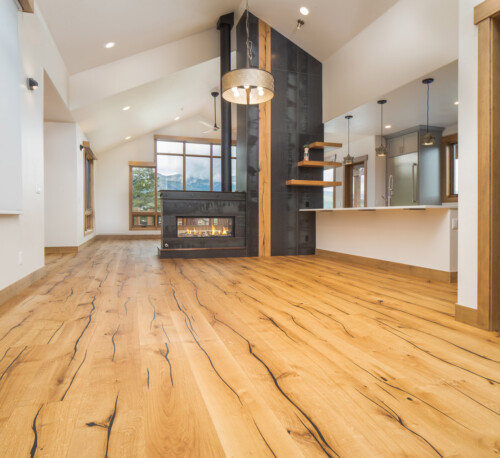 Bright, modern interior with large windows, natural wood flooring, and a cozy fireplace, creating an inviting atmosphere.