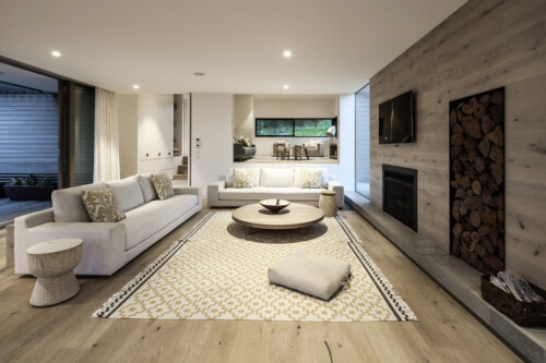 A modern living room featuring a circular coffee table, cozy sofas, a rug, and a wood accent wall, all under soft lighting.