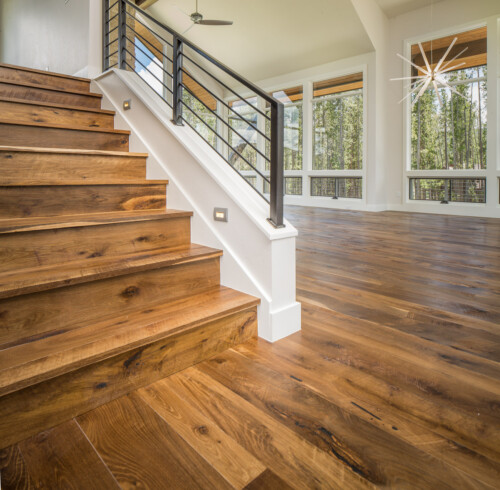 A modern interior featuring wooden stairs leading up to a spacious area with large windows allowing natural light.