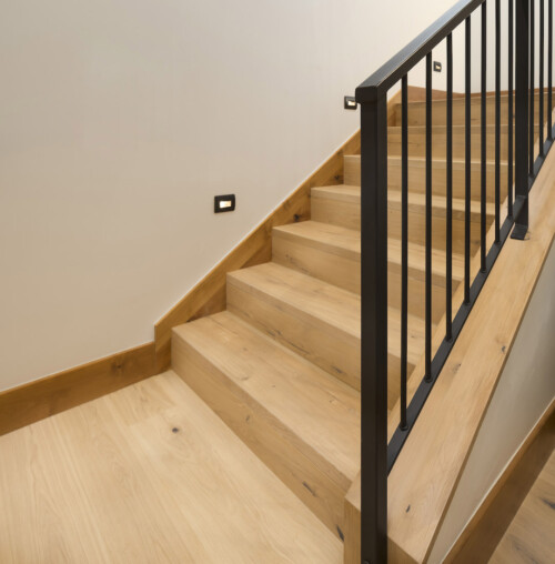 A modern wooden staircase with sleek black railings and warm wooden flooring, providing a clean and contemporary aesthetic.